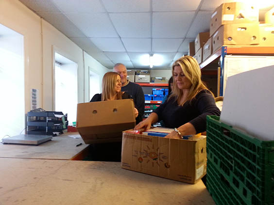 two volunteers lifting boxes in warehouse at foodbank
